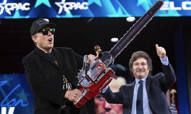 지난 2월20일 미국 메릴랜드주에서 열린 보수정치행동회의(CPAC)에 참석한 일론 머스크가 아르헨티나 대통령 하비에르 밀레이(오른쪽)로부터 받은 전기톱을 들어 보이고 있다. 정부효율부(DOGE)를 이끌며 연방정부 예산 삭감, 공무원 감축을 주도하던 머스크는 이날 “관료주의 혁파를 위한 전기톱”이라며 머리 위로 흔들어 보였다. AP연합뉴스