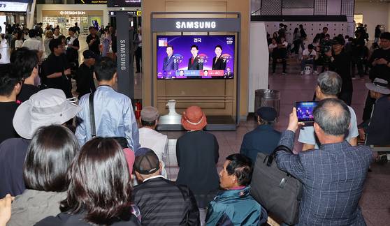 3일 오후 서울 중구 서울역에서 유권자들이 방송3사 출구조사 결과를 TV와 스마트폰으로 확인하고 있다. 뉴스1