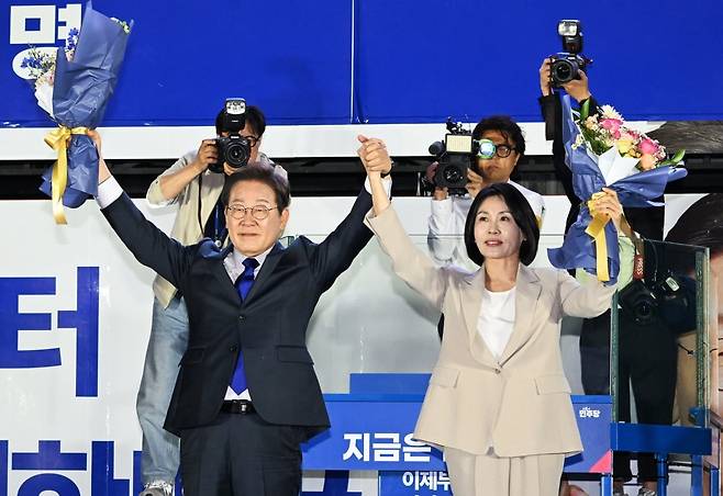 제21대 대통령 당선이 확실시되는 더불어민주당 이재명 대선 후보와 부인 김혜경 여사가 4일 서울 여의도 국회 인근에서 당 주최로 열린 국민개표방송 행사에 참석해 꽃다발을 받고서 시민들을 향해 두 팔을 들어 인사하고 있다. /사진=연합뉴스