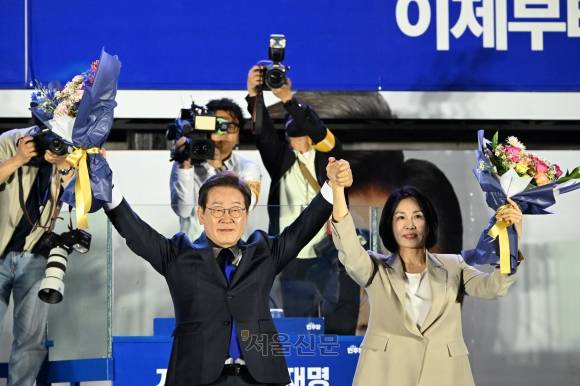이재명(왼쪽) 대통령 당선인과 배우자 김혜경 여사가 4일 서울 여의도 국회 앞에서 당선 축하 꽃다발을 들고 지지자들의 환호에 화답하고 있다. 홍윤기 기자
