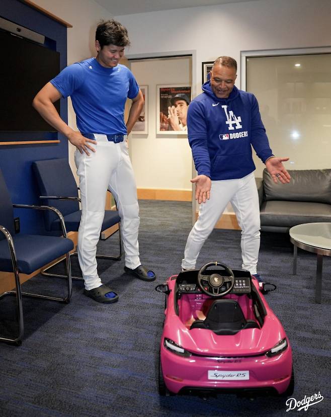 데이브 로버츠 감독이 5일(한국시각) 다저스타디움에서 열린 뉴욕 메츠전을 앞두고 오타니 쇼헤이를 감독실로 불러 그의 딸을 위한 유아용 포르셰 자동차를 선물하며 자랑하고 있다. 사진=LA 다저스 구단 X 계정
