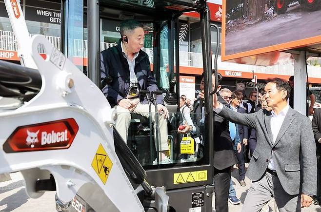 박정원 두산그룹 회장(왼쪽)이 지난달 7~13일(현지시간) 독일 뮌헨에서 열린 건설기계 박람회 ‘2025 바우마’에서 두산밥캣의 유럽시장 주력인 미니굴착기 신제품에 탑승해 스캇 박 두산밥캣 부회장(오른쪽)의 설명을 듣고 있다.ⓒ두산