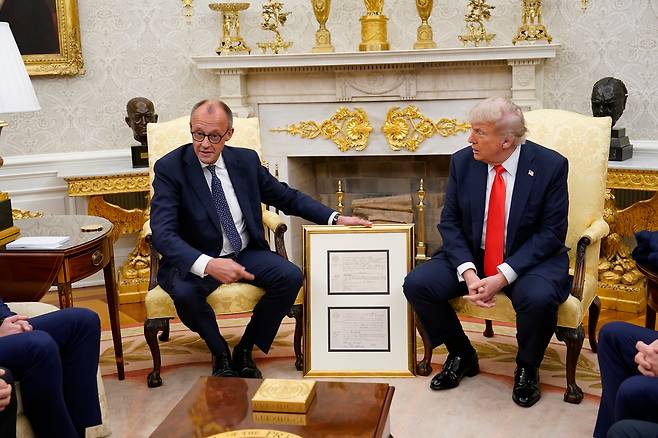 프리드리히 메르츠(왼쪽) 독일 총리가 5일 워싱턴 DC 백악관 집무실에서 도널드 트럼프 미국 대통령과 만나 회담 중 트럼프의 할아버지 프리드리히 트럼프의 독일 출생 증명서를 선물하고 있다. 이번 회담은 메르츠 총리가 5월 초 취임 후 첫 공식 방문이자 두 정상 간 첫 만남이다. /AFP 연합뉴스