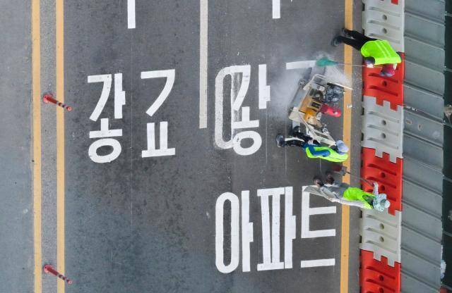 수원특례시 장안구 복합쇼핑몰 스타필드 수원 앞 대로에 ‘광교’ 방면임을 나타내는 도로노면표지가 엉터리 한글로 표기돼 있어 시의 부실한 도로 관리 실태가 도마에 오르고 있다. 사진은 지난 8일 오후 6시5분께 작업자가 문제의 표기를 지우고 있는 모습. 윤원규기자