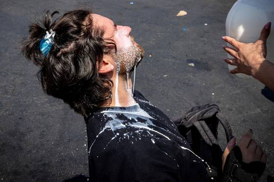 2025년 6월 7일 미국 캘리포니아주 LA에서 한 남성이 최루탄 가스 공격을 받은 뒤 우유를 부어 눈과 얼굴을 씻어 내고 있다. 로이터=연합뉴스