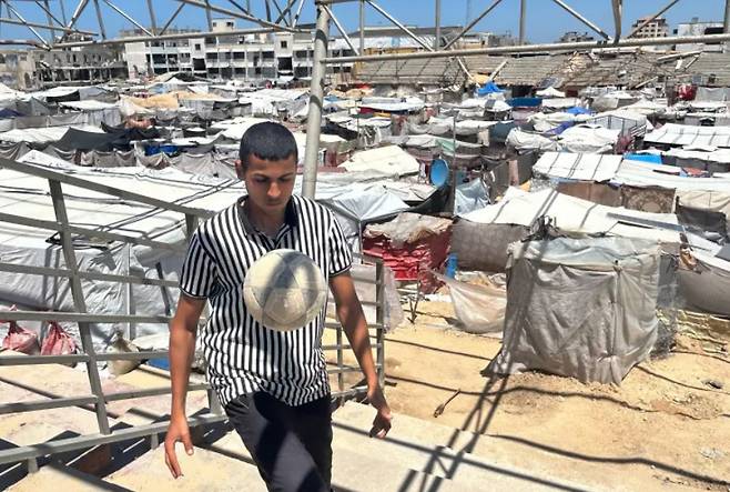 팔레스타인 가자지구 남부 도시 라파에 있는 축구리그 소속으로 뛰던 20세 골키퍼 유세프 아부 샤와리브가 피란민들을 위한 수백개의 천막으로 가득 차버린 축구경기장에서 공을 차고 있다. 알자지라 캡처