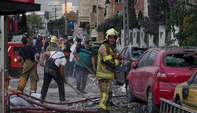 이란 구조 당국이 13일(현지시간) 이란 테헤란 북부에서 이스라엘군의 공습을 받은 지역을 수색하고 있다. ⓒAP/뉴시스