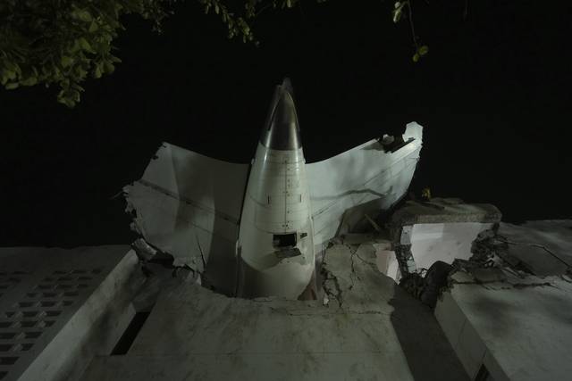 인도 구자라트주 아흐메다바드 공항에서 이륙했다 추락한 비행기의 후미 부분이 사고 현장에 있는 건물에 충돌해 꽃혀 있다. AP 연합뉴스