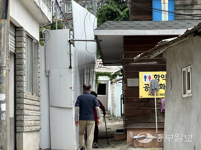 인천 미추홀구 학익소로 63번길에 위치한 공용화장실을 이용하는 인근 주민들의 모습. 맞은편 휀스 일부가 붕괴된 빈집의 무게를 이기지 못하고 휘어져 있다. 사진=장수빈기자