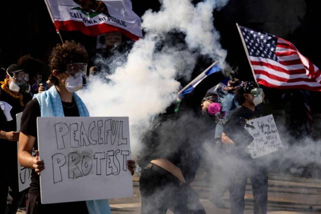 트럼프 대통령의 군사 퍼레이드가 열린 14일, 로스앤젤레스에서 열린 트럼프 행정부에 반대하는 '노 킹스(No Kings)' 시위에서 당국이 불법 집회를 선포한 후 발생한 충돌에서 한 시위자가 법 집행 기관에 최루탄을 던지고 있다. AFP연합뉴스