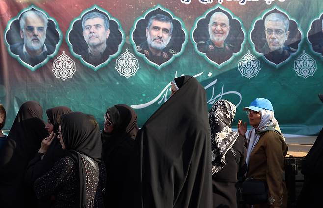 지난 13일 이스라엘의 이란 공습으로 사망한 이란 군 수뇌부와 핵물리학자들의 얼굴이 걸린 현수막 앞을 지나가고 있는 이란 여성들. 이들 요인의 동선은 이스라엘 정보기관 모사드가 손바닥을 들여다보듯 파악하고 있었던 것으로 알려졌다./로이터 연합뉴스