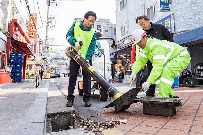 최호권 영등포구청장(왼쪽)이 직원들과 함께 빗물받이에 쌓인 담배 꽁초 청소를 하고 있다.