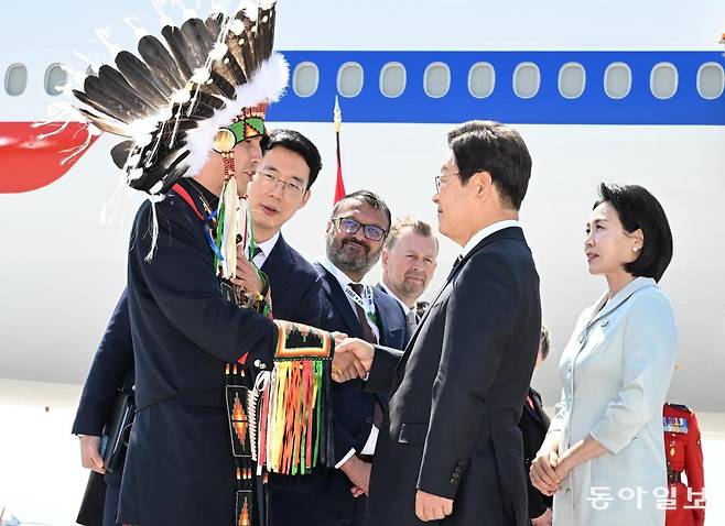 이재명 대통령과 김혜경 여사가 16일 (현지시간) G7 정상회의에 참석하기 위해 캘거리공항에 도착해 환영나온 인디언 복장을 한 스티븐 크로우차일드 추트이나 부족 족장과 악수를 하고 있다. 캘거리=송은석 기자 silverstone@donga.com