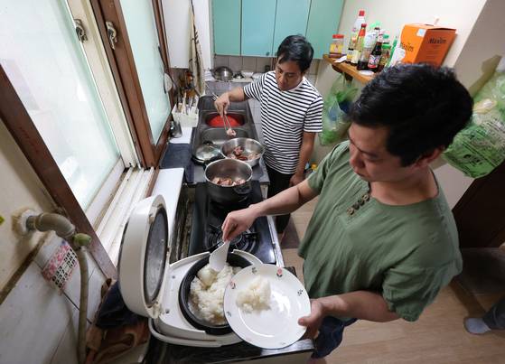 지난 5일 경남 거제시 투룸 숙소에서 대형 조선소 사내협력사 소속 외국인 근로자 쏘꼬꼬한(38·미얀마·사진 왼쪽)과 그의 동료가 직접 구입한 돼지 족발 덩어리를 냄비에 삶고, 밥솥에 밥을 지어 저녁 식사를 준비하고 있다. 송봉근 기자