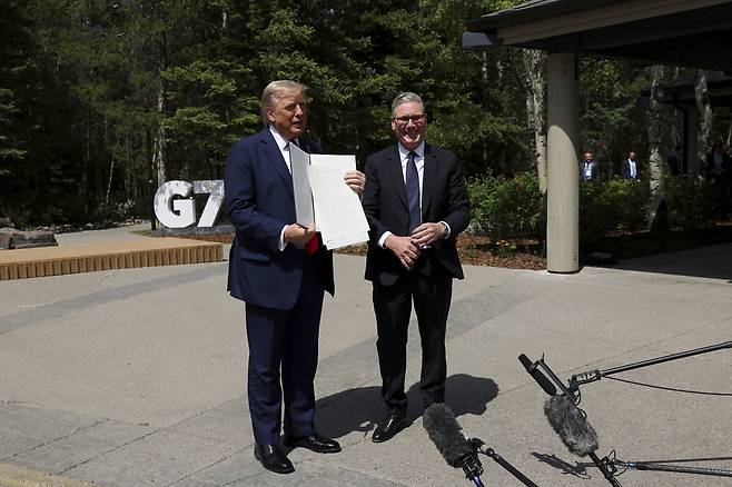 도널드 트럼프 미국 대통령(왼쪽)이 16일(현지시간) 캐나다 앨버타주 캐내내스키스에서 키어 스타머 영국 총리와의 정상회담 후 서명한 미·영 무역협정 문서를 들어 보이고 있다. AP연합뉴스