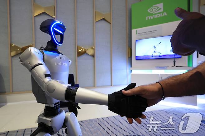 세계 최대 가전·정보기술(IT) 전시회 CES 2025 개막일인 7일(현지시간) 젠슨 황 엔비디아 최고경영자(CEO) 글로벌 기자간담회가 열린 미국 네바다주 라스베이거스 퐁텐블루 호텔에 마련된 엔비디아 전시관에서 휴머노이드 로봇 유니트리 G1이 관람객과 악수하고 있다. (공동취재) 2025.1.8/뉴스1 ⓒ News1 신웅수 기자