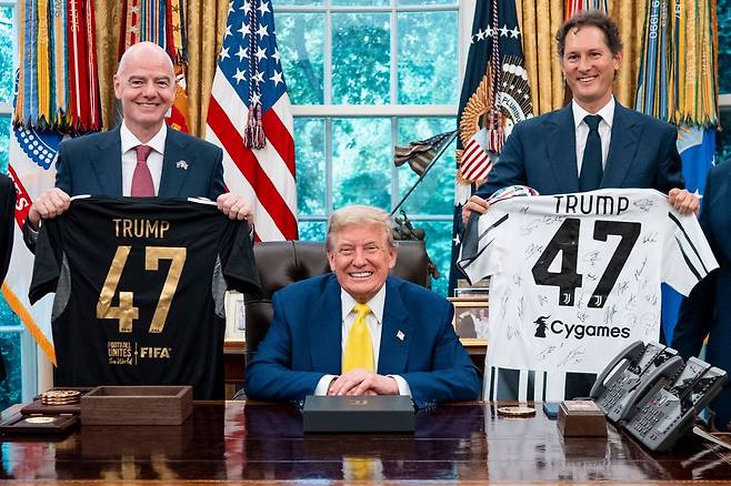 도널드 트럼프 미국 대통령이 18일(현지시간) 백악관 집무실에서 열린 이탈리아 축구팀 유벤투스가 방문 행사에서 지아니 인판티노 FIFA 회장(왼쪽), 존 엘칸 페라리 회장과 유니폼을 들고 있다. 연합뉴스