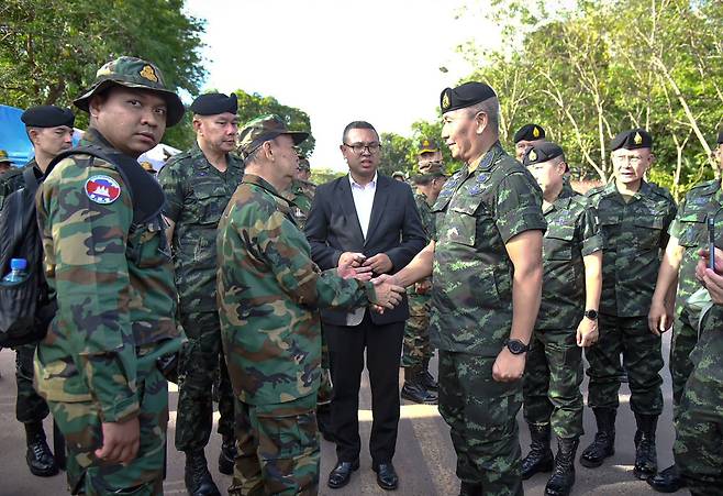 태국 왕립군 총사령관 파나 클라우플로드툭 장군(오른쪽)과 캄보디아 장군 마오 소판(왼쪽)이 지난달 태국 수린주 캅초엥 지역 태국-캄보디아 국경에서 악수하고 있다. /연합뉴스