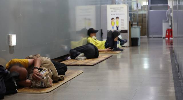 ▲ 전국 대부분 지역에서 최고 체감온도가 35도 안팎으로 오르던 지난 2023년 8월 초 서울역희망지원센터에서 노숙인 등이 복도에 누워 휴식하고 있다. ⓒ연합뉴스