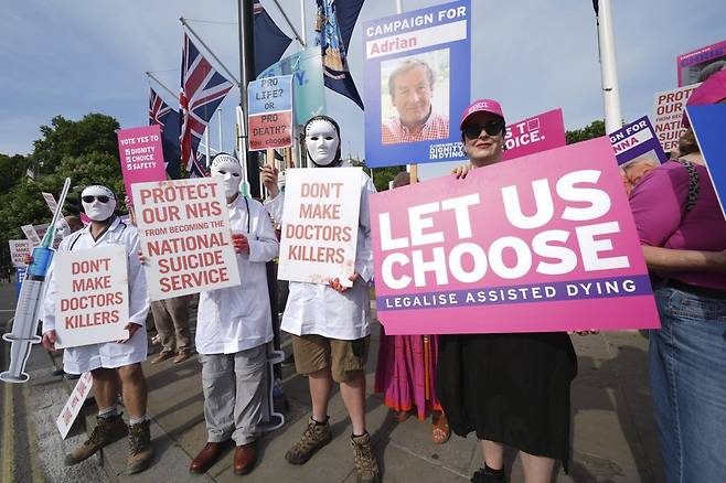 영국 하원에서 20일(현지 시간) 안락사를 허용하는 법안에 대한 투표가 진행되는 동안 법안에 찬성하는 사람들과 반대하는 사람들이 각자의 주장이 담긴 손팻말을 들고 결과를 기다리고 있다. AP=뉴시스