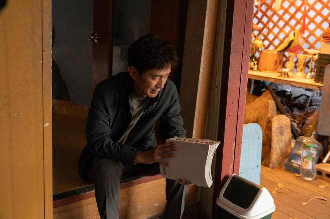 배우 안내상은 영화 <신명>에서 ‘열공TV’ 탐사보도 기자 정현수 PD를 연기했다. 그가 든 책면에는 ‘김석일(윤석열 전 대통령을 풍자한 캐릭터) 9수’라고 적혀 있다. 열공영화제작소 제공