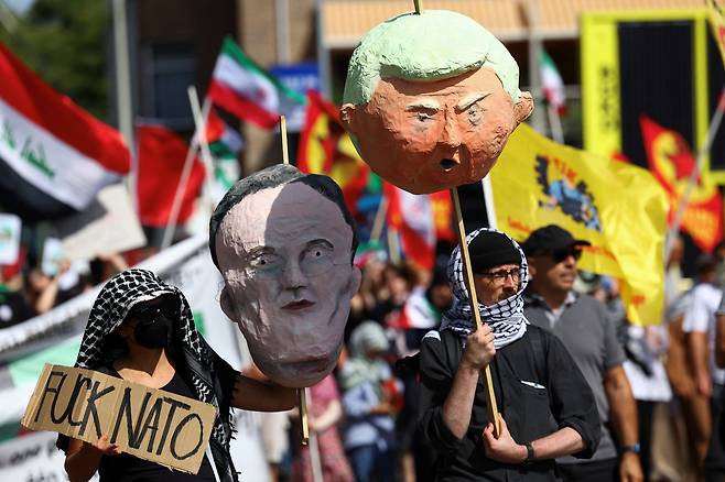 시위대가 22일 네덜란드 헤이그에서 열리는 NATO 정상회담에 반대하는 시위를 벌이면서 NATO 사무총장 마크 뤼터와 미국 대통령 도널드 트럼프 모습이 담긴 종이인형 두상을 들고 있다. /연합뉴스