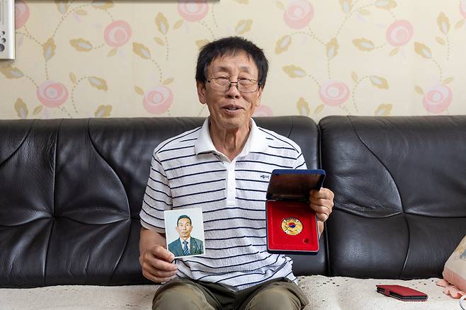 장병윤(78)씨가 아버지 故 장경본 중사의 사진을 들고 포즈를 취하고 있다. 최지원 기자