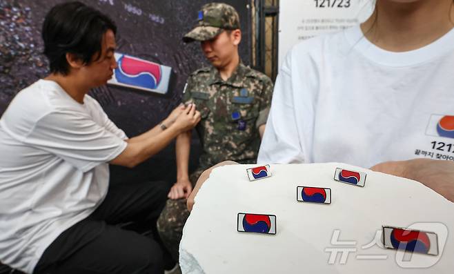 25일 서울 중구 서울역 대합실에 마련된 '태극기 부스'에서 군인들이 태극기 배지를 패용하고 있다. 2025.6.25/뉴스1 ⓒ News1 김도우 기자