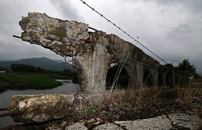 강원도 철원군 김화읍 암정리와 용양리를 잇는 암정교. 한국전쟁 당시 폭격으로 일부가 파괴됐고, 전쟁의 상흔을 고스란히 간직한 채 민간인출입통제선 안에 서 있다. 다리 곳곳은 무너지고 갈라져 콘크리트와 자갈, 시뻘건 철근이 보인다. 북쪽에서 발원한 화강(꽃강)이 흐르고 저 멀리 천불산 자락이 보인다.