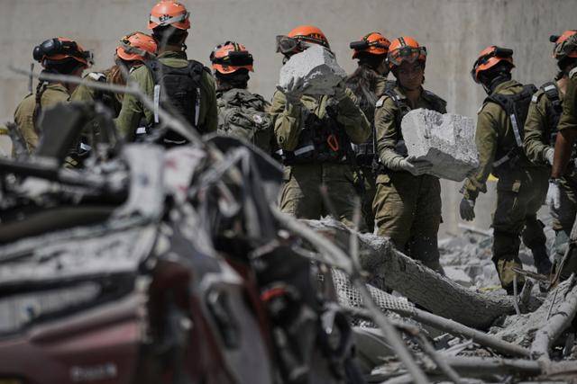 이스라엘 군인들이 24일 이란 미사일 공격을 받아 민간인들이 다수 사망한 건물 붕괴 현장을 정리하고 있다. 브엘세바(이스라엘)=AP연합뉴스
