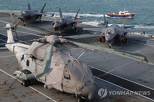 영국 항공모함 함상의 헬리콥터와 전투기 (싱가포르 로이터=연합뉴스) 2025년 6월 24일 싱가포르의 마리나베이 크루즈 센터에 입항해 있는 영국 해군 항공모함 '프린스오브웨일스' 함상 비행갑판에 멀린 헬리콥터 한 대와 F-35B 라이트닝 Ⅱ 몇 대가 세워져 있다. (REUTERS/Edgar Su) 2025.6.25.