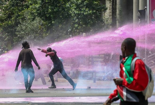 25일 케냐 나이로비 중심업무지구에서 열린 시위에 참여한 시민들이 물대포를 맞고 있다. 이번 시위는 국회의사당 난입으로 이어졌던 ‘Z세대 시위’ 1주년을 기념하는 자리다. EPA 연합뉴스