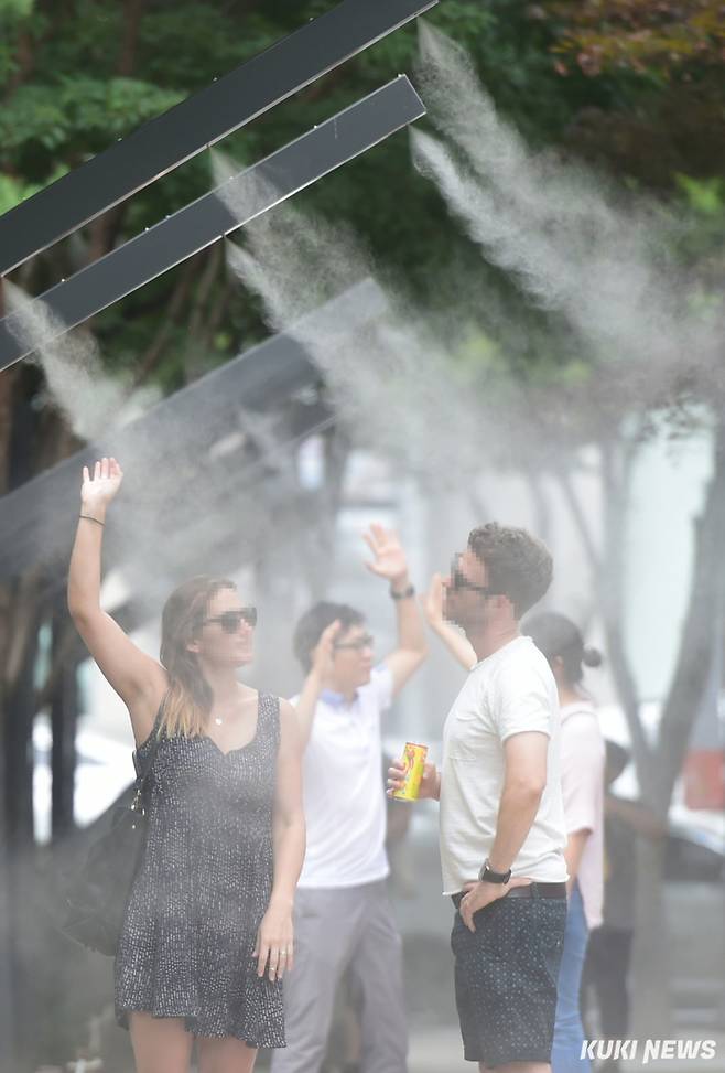 시민과 외국인 관광객이 쿨링포그(안개분사장치) 밑에서 더위를 식히고 있다. 자료사진=최태욱 기자