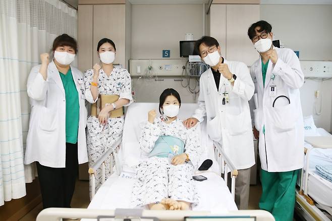 다낭성 신증후군으로 만성 신부전을 앓던 이가영 씨(가운데)가 로봇 신장이식 후 순조롭게 회복하며 20일(금) 의료진과 기념사진을 찍고 있다. 왼쪽에서 두 번째가 공여자인 언니 이 모 씨, 네 번째가 수술을 집도한 서울아산병원 신·췌장이식외과 신성 교수