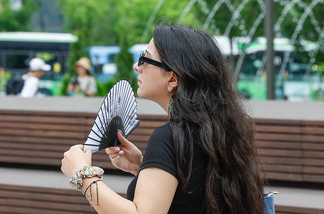 서울 최고온도 33도까지 올라 습하고 더운 날씨를 보인 2일 서울 종로구 광화문광장에서 한 외국인 관광객이 부채를 부치고 있다.