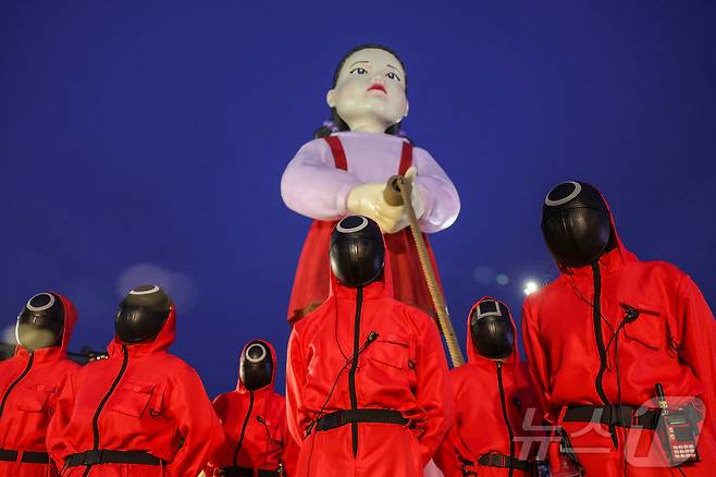 지난 30일(현지시간) 태국 방콩 시청 광장에서 열린 '오징어 게임 3' 홍보 행사에서 핑크 복장의 진행요원들이 '영희' 인형과 함께 촬영을 하고 있다. ⓒ 로이터=뉴스1