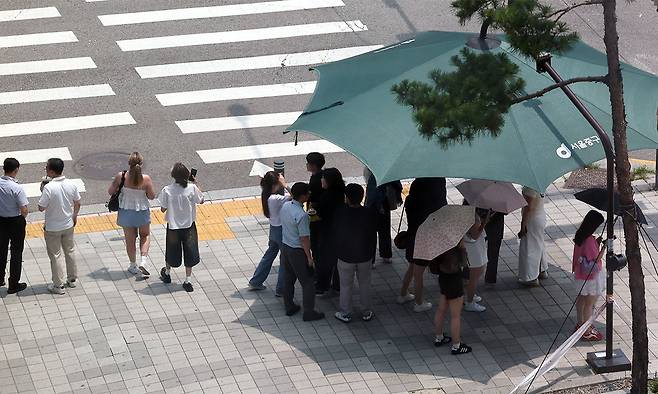 8일 서울 중구 을지로1가사거리에서 시민들이 햇볕을 피해 그늘막 아래서 신호를 기다리고 있다. 뉴시스
