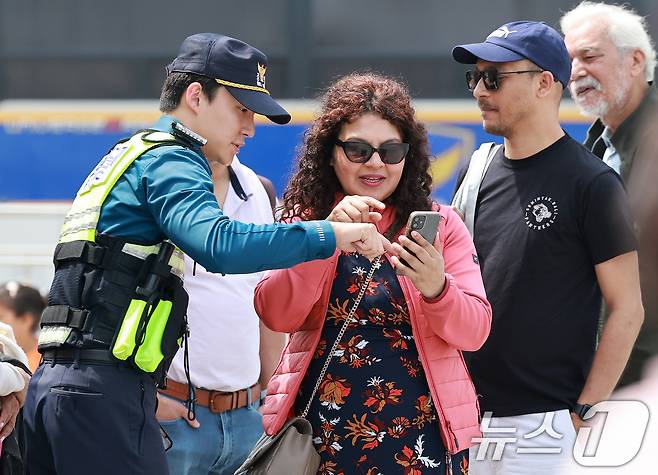 서울 종로구 광화문광장을 찾은 외국인 관광객들이 경찰관의 안내를 받고 있다. 2025.4.18/뉴스1 ⓒ News1 김진환 기자