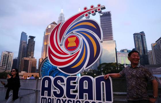 지난 8일(현지시간) 말레이시아 쿠알라룸푸르에서 행인들이 아세안 관련 회의 로고 옆에서 포즈를 취하는 모습. 로이터=연합뉴스