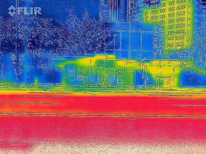 연일 폭염특보가 이어지고 있는 10일 오전 광주 서구 한 버스정류장을 열화상 카메라로 촬영한 모습. 온도가 낮은 곳은 푸르게, 높은 곳은 붉게 표시돼 있다.