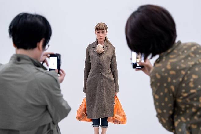 관람객들이 론 뮤익 작품 '쇼핑하는 여인'을 감상하고 있다. 양손에 묵직한 쇼핑 봉투를 든 채 외투 속에 아기를 품고 있는 여성 조각이다. 아기는 작은 손가락을 엄마 가슴에 얹고 간절하게 엄마를 올려다보지만, 피곤에 지친 엄마는 생각에 잠겨 다른 곳을 보고 있다. /국립현대미술관