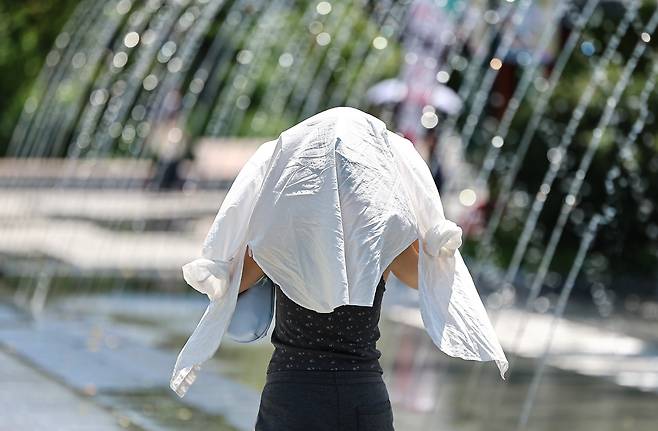 폭염이 이어진 10일 서울 종로구 광화문광장에서 한 시민이 옷으로 얼굴을 가린채 이동하고 있다. /뉴스1