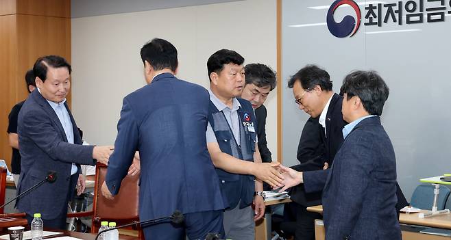 10일 저녁 세종시 정부세종청사 고용노동부에서 열린 최저임금위원회 제12차 전원회의에서 사용자위원과 한국노총 근로자위원들만이 참여하여 2026년 최저임금을 10,320원으로 합의하며 류기정 사용자위원과 류기섭 근로자위원 등이 회의장을 떠나며 인사를 나누고 있다./뉴스1