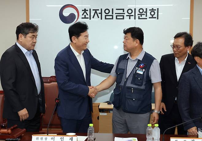 최저임금위원회 사용자위원 운영위원인 류기정 한국경영자총협회 전무(왼쪽)와 근로자위원 운영위원인 류기섭 한국노총 사무총장이 10일 정부세종청사에서 열린 제12차 전원회의에서 내년 최저임금을 시간당 1만320원으로 17년 만에 합의로 결정한 뒤 악수하고 있다. 왼쪽은 이인재 위원장, 오른쪽은 이명로 중소기업중앙회 인력정책본부장. 연합뉴스.