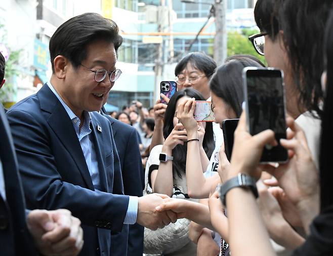 이재명 대통령이 11일 저녁 외식 행사가 열린 서울 종로구의 한 식당으로 걸어서 이동하던 도중 시민들과 인사하고 있다. 대통령실사진기자단