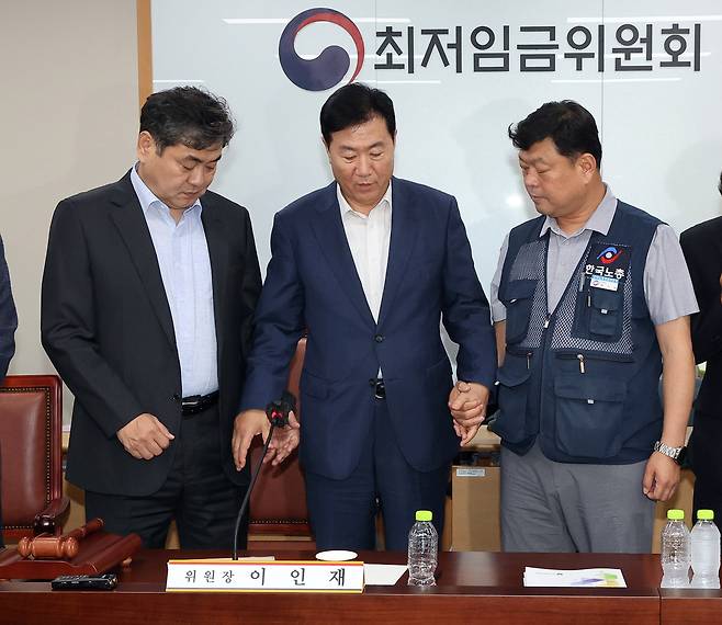 지난 10일 정부세종청사에서 열린 제12차 전원회의에서 내년 최저임금을 시간당 1만320원으로 17년만에 합의로 결정한 뒤 이인재 위원장(왼쪽부터), 사용자위원인 류기정 한국경영자총협회 전무, 근로자위원인 류기섭 한국노총 사무총장이 기념촬영을 위해 손을 잡고 있다. 연합뉴스