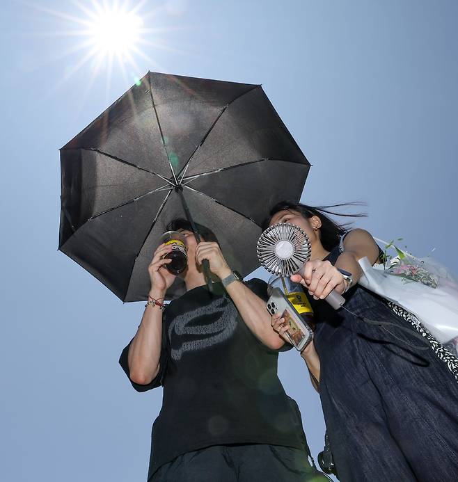 118년 만에 수도권을 덮친 극한 폭염이 나타난 11일 오후 경기 수원시 행궁동 일대에서 시민들이 양산을 쓴 채 손풍기를 이용하고 아이스 음료를 마시며 더위를 달래고 있다. /박성원 기자