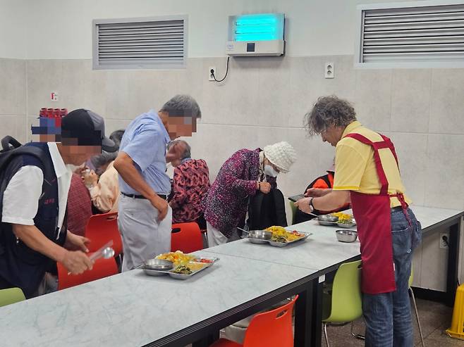 김하종 신부가 무료급식으로 제공된 식사 상태를 확인하고 있다./사진=박상혁 기자.