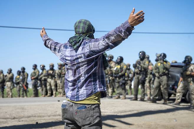 지난 10일 미국 캘리포니아주의 한 농업 지역에서 연방 이민국 요원들과 시위대가 대치하고 있다. AP연합뉴스