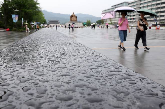 지난 13일 서울 종로구 광화문광장에서 우산을 쓴 시민들이 발걸음을 옮기고 있다. 뉴시스